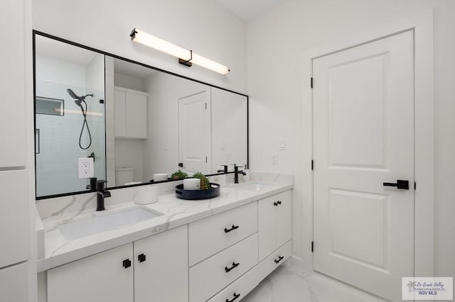 bathroom featuring a sink, toilet, marble finish floor, and a stall shower