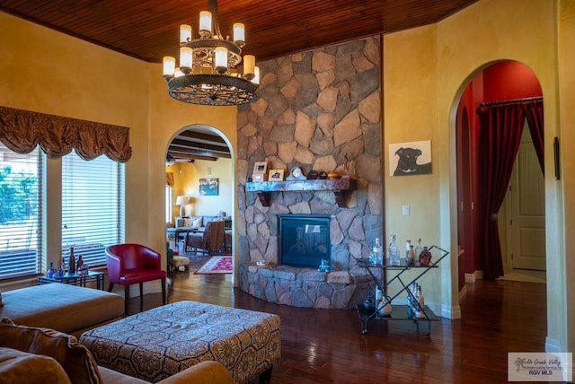 living room featuring dark wood-type flooring, wood ceiling, a fireplace, and a chandelier