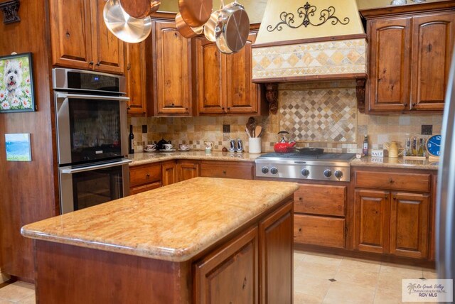 4329 Waters Edge, Harlingen, TX 78550 - kitchen featuring premium range hood, appliances with stainless steel finishes, decorative backsplash, light stone countertops, and a center island