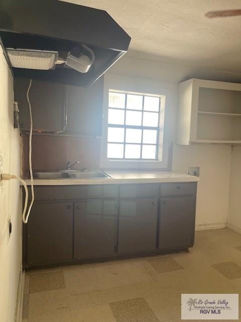 kitchen with sink, exhaust hood, and a textured ceiling