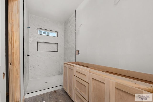 full bath with a marble finish shower and wood finished floors