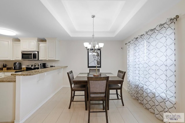 tiled dining area with an inviting chandelier and a tray ceiling