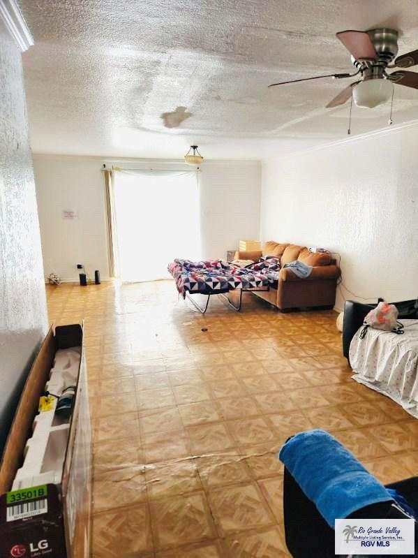 living room featuring ceiling fan and a textured ceiling