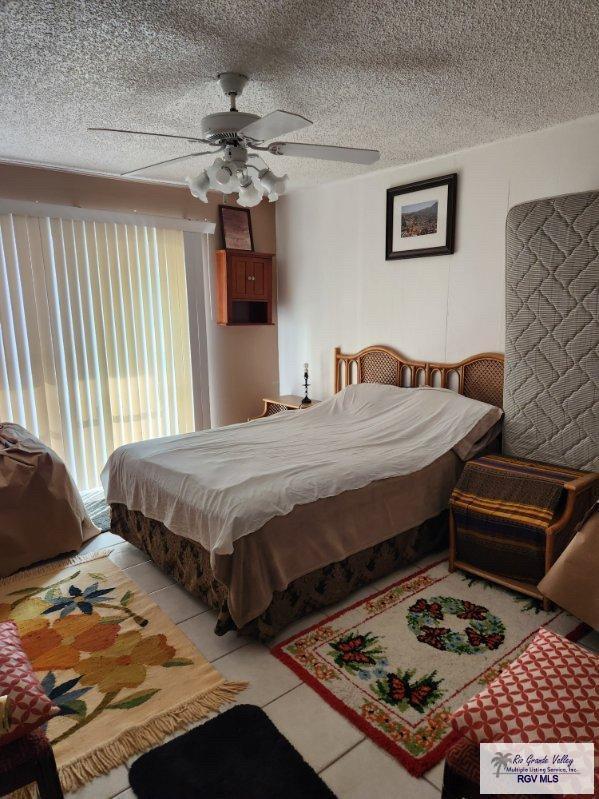 bedroom featuring ceiling fan, a textured ceiling, and light tile patterned floors