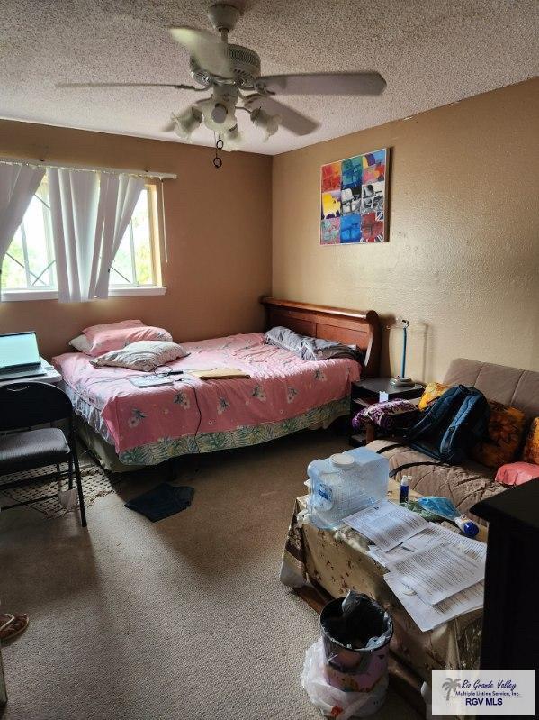 bedroom featuring ceiling fan, carpet floors, and a textured ceiling