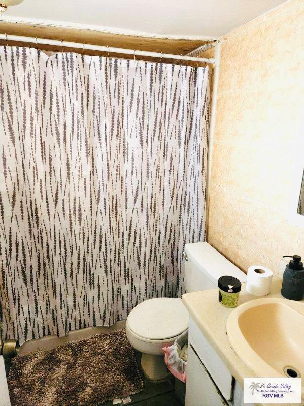 bathroom with vanity, tile walls, and toilet