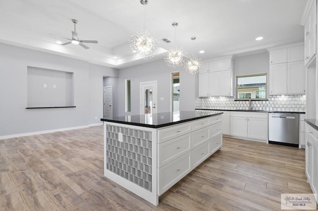 kitchen featuring recessed lighting, dark countertops, dishwasher, and a sink