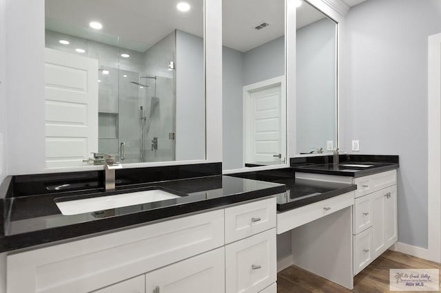 bathroom with wood finished floors, vanity, baseboards, visible vents, and a stall shower
