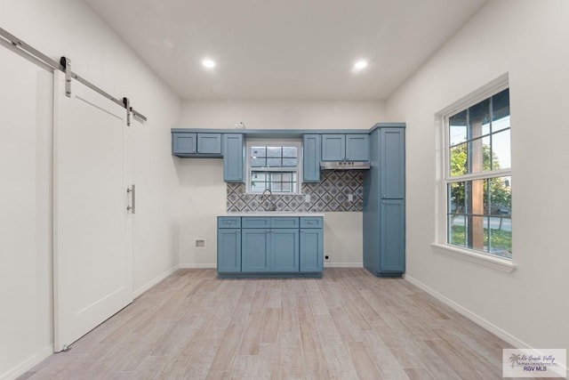 861 Rio Grande St, San Benito, TX 78586 - kitchen featuring a barn door, blue cabinetry, light wood-style flooring, tasteful backsplash, and recessed lighting
