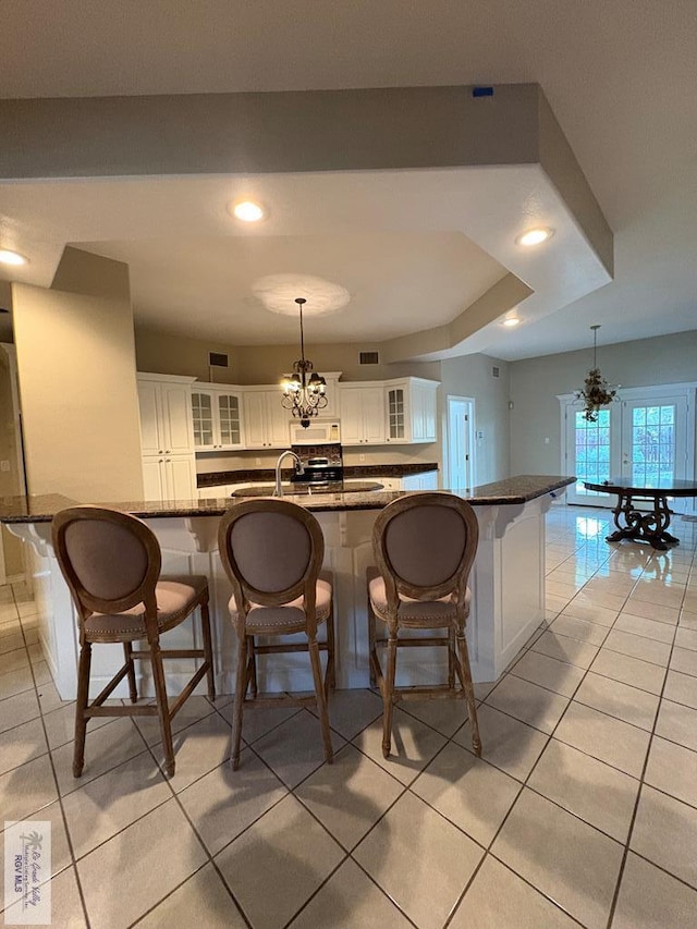 901 Plantation St, Brownsville, TX 78526 - kitchen featuring a chandelier, a breakfast bar, white cabinets, glass insert cabinets, and pendant lighting