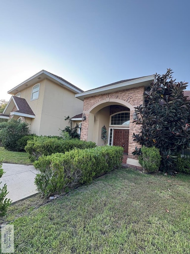 901 Plantation St, Brownsville, TX 78526 - view of front of home with a front yard, stucco siding, and stone siding