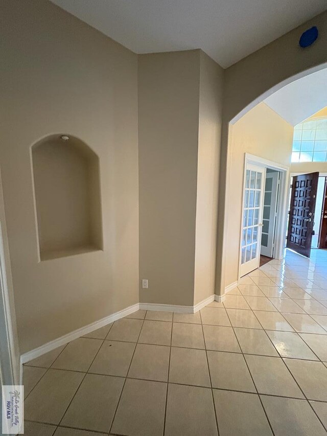 901 Plantation St, Brownsville, TX 78526 - empty room featuring arched walkways, light tile patterned flooring, baseboards, and french doors