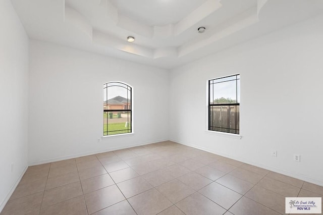 empty room featuring light tile patterned flooring and a tray ceiling