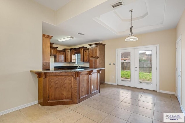 kitchen featuring kitchen peninsula, a breakfast bar area, light tile patterned flooring, french doors, and hanging light fixtures