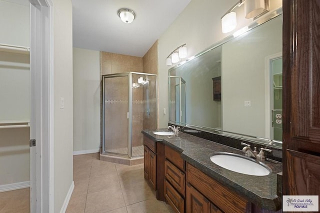 bathroom with a shower with shower door, vanity, and tile patterned flooring