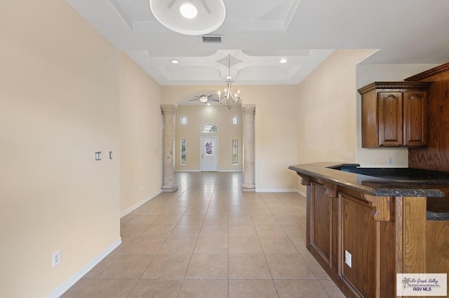 kitchen featuring light tile patterned flooring, hanging light fixtures, a breakfast bar area, a chandelier, and decorative columns