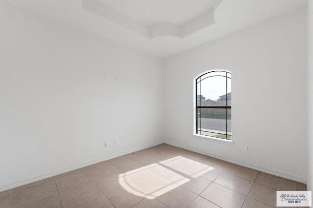 tiled spare room featuring a raised ceiling