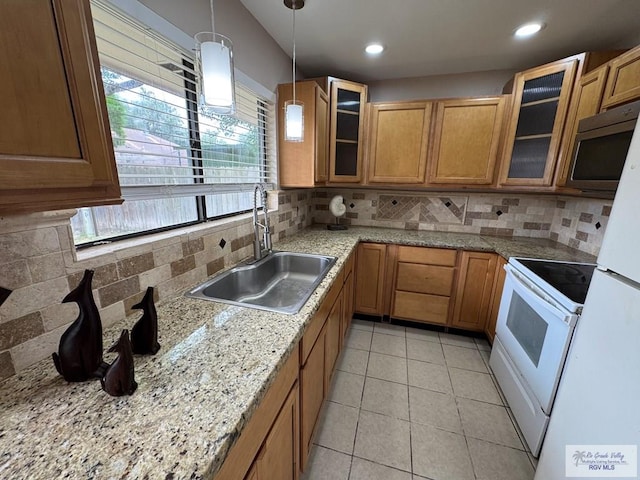 2805 Swiss Pine Ct, Harlingen, TX 78550 - kitchen featuring stainless steel microwave, a sink, tasteful backsplash, brown cabinetry, and hanging light fixtures