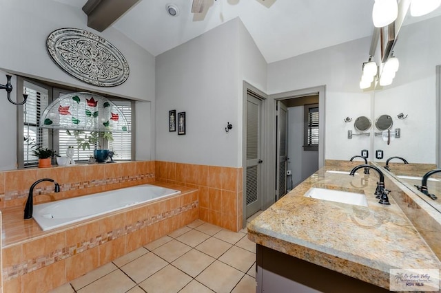 bathroom with tile patterned floors, vaulted ceiling with beams, vanity, and tiled tub