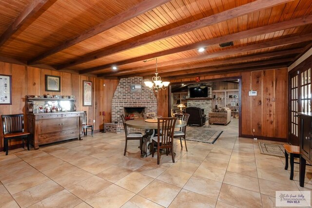 tiled dining room with beam ceiling, wood walls, a fireplace, and wood ceiling