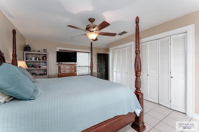 tiled bedroom with ceiling fan and multiple closets