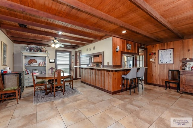 kitchen with kitchen peninsula, ceiling fan, wooden walls, wooden ceiling, and beamed ceiling