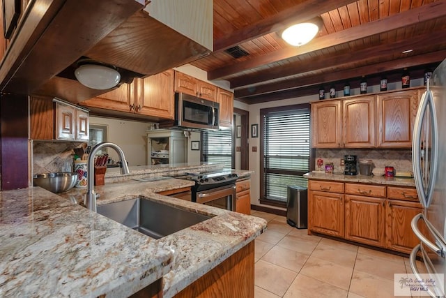 kitchen with backsplash, light stone counters, stainless steel appliances, sink, and light tile patterned floors