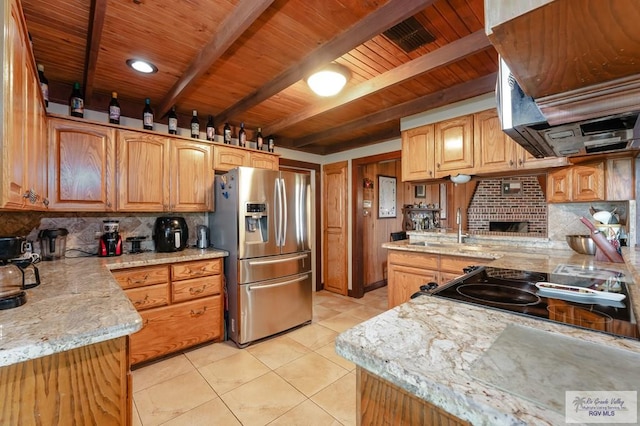 kitchen with light stone countertops, stainless steel fridge, light tile patterned floors, and sink