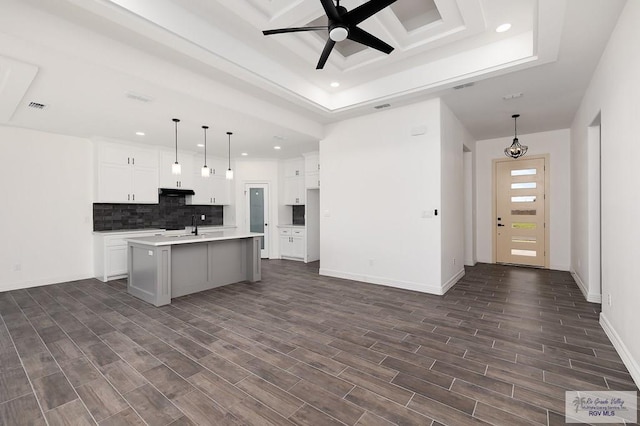 kitchen featuring white cabinets, decorative light fixtures, a center island with sink, and dark hardwood / wood-style floors