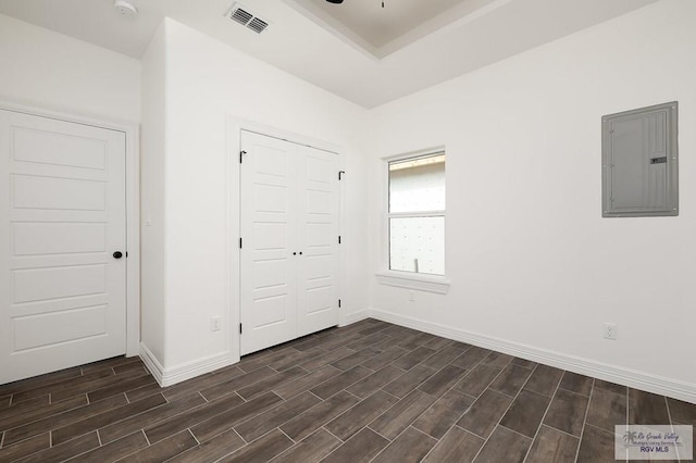 unfurnished bedroom with dark hardwood / wood-style floors, electric panel, and a closet