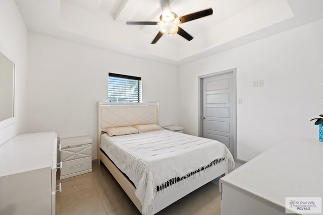 bedroom featuring a raised ceiling, ceiling fan, and light tile patterned floors