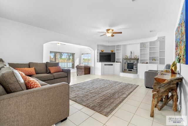 tiled living room featuring ceiling fan and built in features