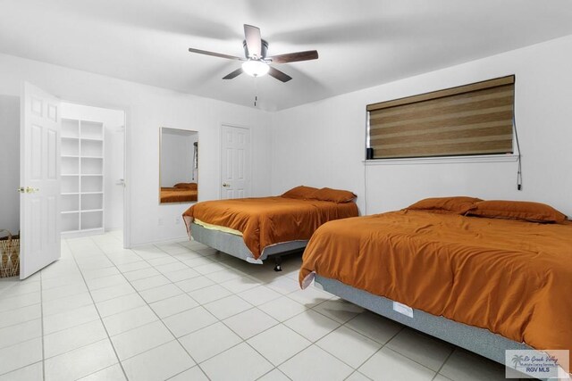 tiled bedroom featuring a walk in closet and ceiling fan