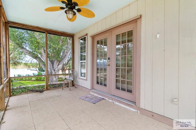 unfurnished sunroom featuring ceiling fan and french doors