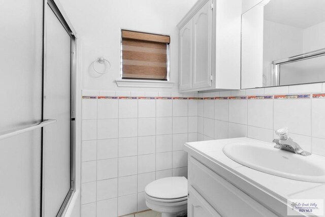 bathroom with vanity, tile walls, and toilet