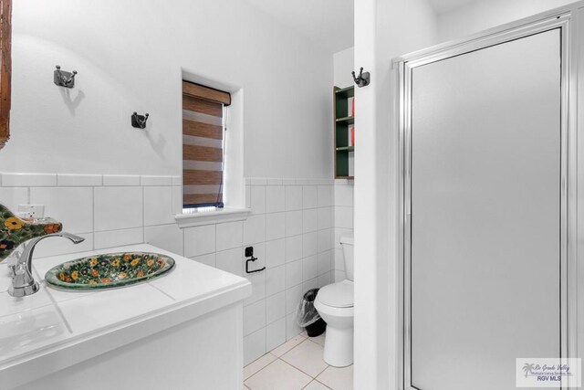 bathroom with vanity, tile patterned flooring, toilet, tile walls, and walk in shower