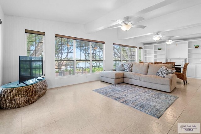 tiled living room featuring beam ceiling, plenty of natural light, built in shelves, and ceiling fan