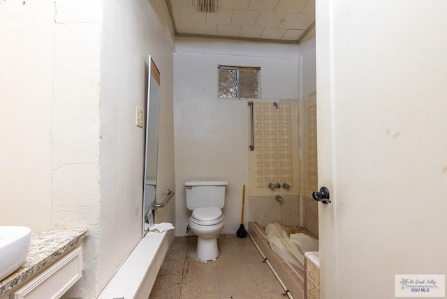 bathroom featuring tiled shower, vanity, and toilet