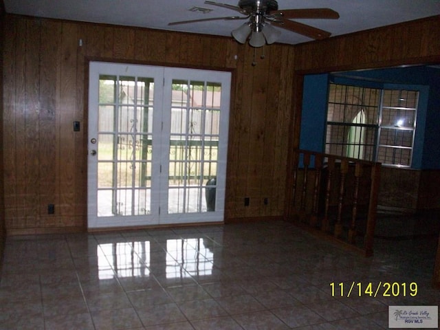 empty room with tile patterned flooring, ceiling fan, and wooden walls