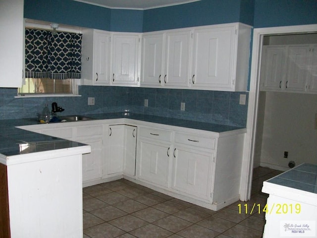 kitchen featuring white cabinetry, kitchen peninsula, decorative backsplash, and light tile patterned floors