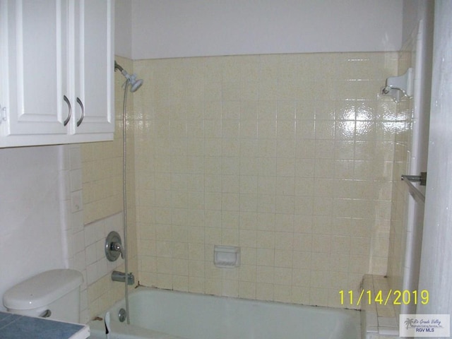 bathroom with tiled shower / bath combo and toilet