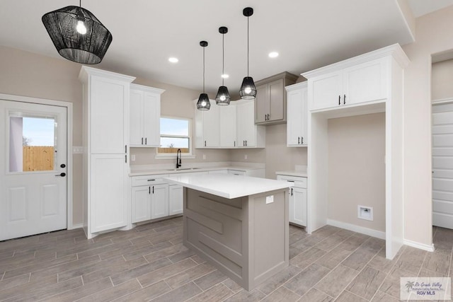 kitchen with white cabinetry, sink, a kitchen island, and decorative light fixtures