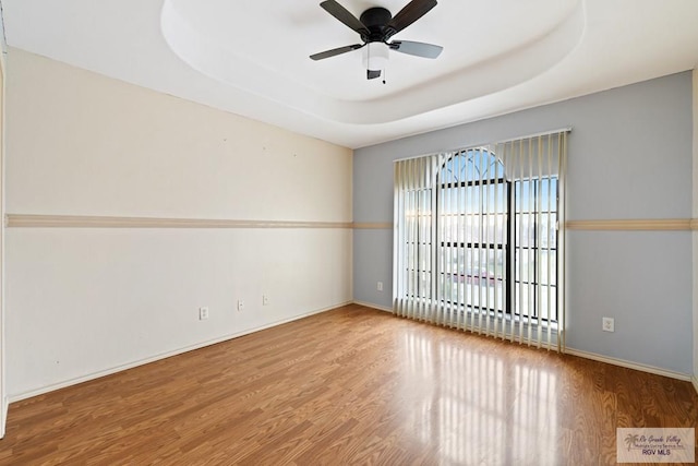 unfurnished room featuring ceiling fan, hardwood / wood-style floors, and a raised ceiling