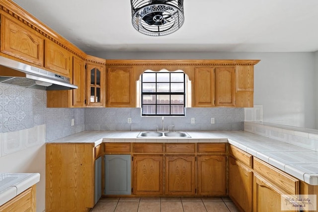 kitchen featuring sink, light tile patterned floors, tile counters, and tasteful backsplash