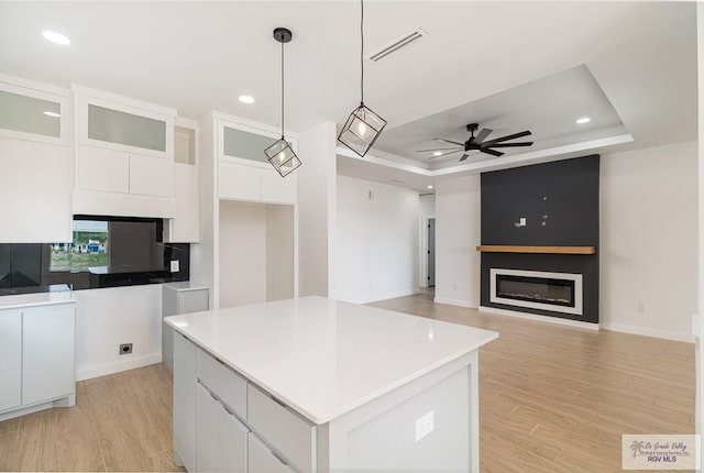 660 Tamarindo Ln Unit 2, Brownsville, TX 78521 - kitchen featuring a large fireplace, white cabinets, a ceiling fan, a center island, and a raised ceiling