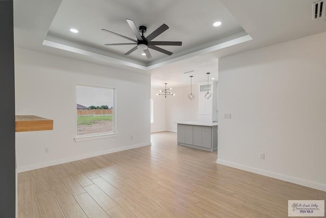 660 Tamarindo Ln Unit 2, Brownsville, TX 78521 - empty room featuring a raised ceiling, ceiling fan, light wood-style flooring, a chandelier, and recessed lighting