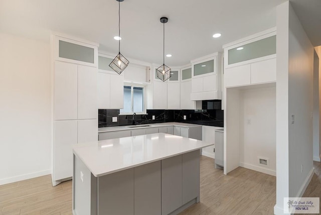 660 Tamarindo Ln Unit 2, Brownsville, TX 78521 - kitchen with light wood-type flooring, tasteful backsplash, white cabinetry, a kitchen island, and glass insert cabinets