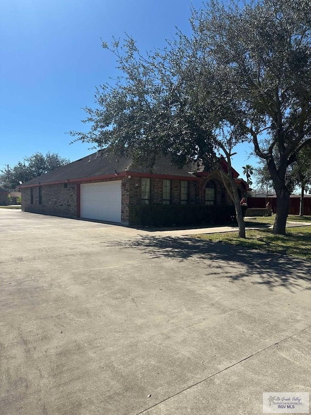 view of front of house featuring driveway, brick siding, and an attached garage