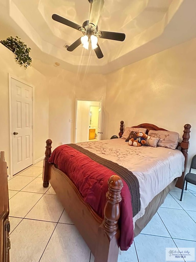 bedroom featuring light tile patterned floors, ceiling fan, and a raised ceiling