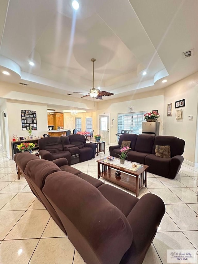 living room with visible vents, a tray ceiling, and light tile patterned flooring